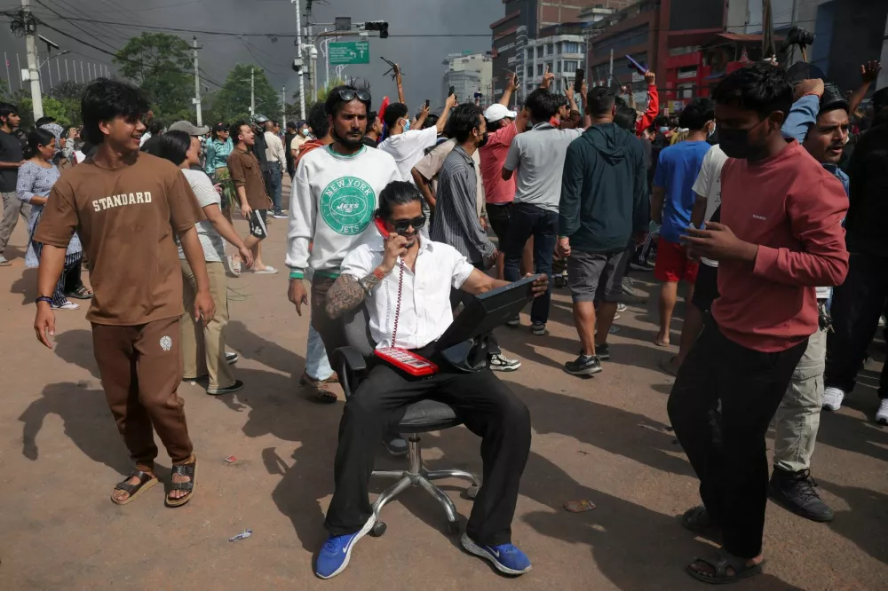 A demonstrator sits on a chair holding a monitor and phone taken from Parliament during a protest against Monday's killing of 19 people after anti-corruption protests that were triggered by a social media ban, which was later lifted, during a curfew in Kathmandu, Nepal, September 9, 2025. REUTERS/Adnan Abidi      TPX IMAGES OF THE DAY