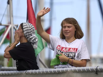 Swedish climate activist Greta Thunberg waves from a boat taking part in a civilian flotilla bound for Gaza, aiming to break the Israeli blockade and deliver humanitarian aid, in Barcelona, Spain, Sunday, Aug. 31, 2025. (AP Photo/Emilio Morenatti)