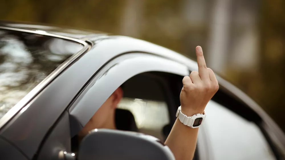 young driver shows middle finger, natural light, selective focus