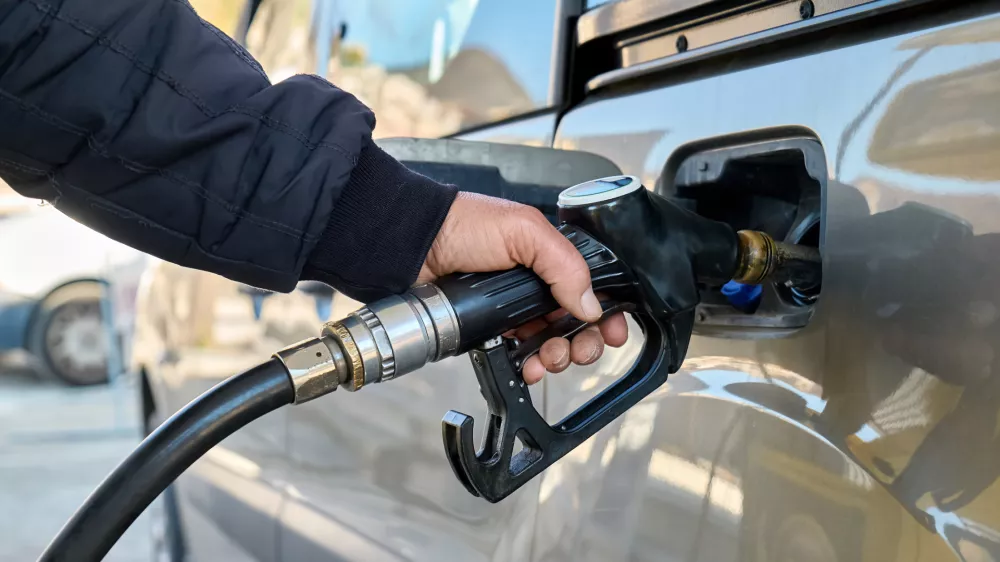 Hand of man driver holding fuel pump and refilling gasoline tank of car with fuel at gas station. / Foto: Ekaterina Fedulyeva