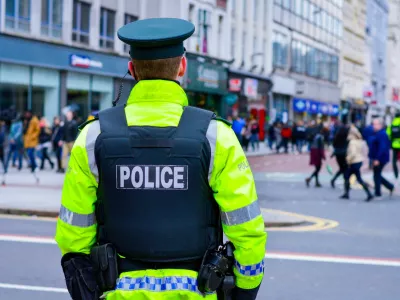 Belfast, Northern Ireland, UK, March 17, 2018. Back view of a policeman in a busy street at Belfast city centre during St Patrick's Day celebration, Northern Ireland.