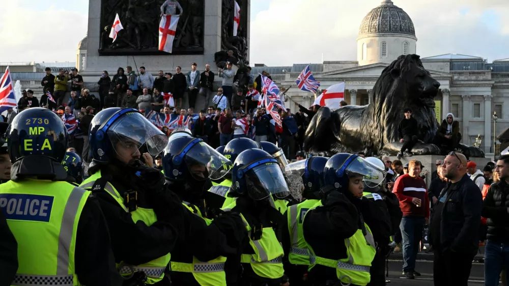 Police officers stand guard next to supporters of British anti-immigration activist Stephen Yaxley-Lennon, also known as Tommy Robinson, during a rally, in London, Britain, September 13, 2025. REUTERS/Chris J. Ratcliffe