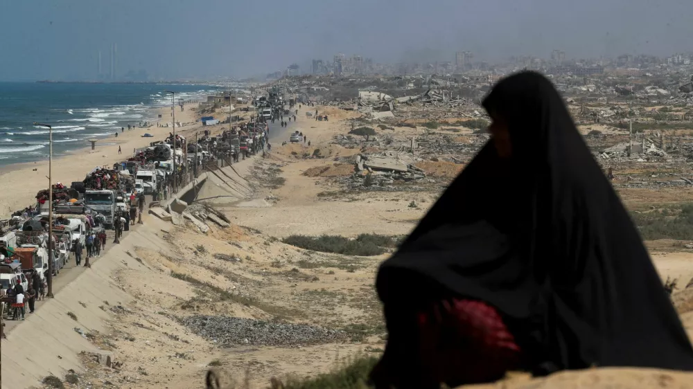 A woman observes, as displaced Palestinians, fleeing northern Gaza due to an Israeli military operation, move southward after Israeli forces ordered residents of Gaza City to evacuate to the south, in the central Gaza Strip, September 17, 2025. REUTERS/Mahmoud Issa   TPX IMAGES OF THE DAY