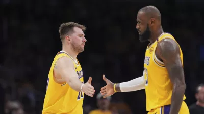 Los Angeles Lakers guard Luka Doncic, left, touches hands with teammate forward LeBron James during the first half of an NBA basketball game against the Utah Jazz, Monday, Feb. 10, 2025, in Los Angeles. (AP Photo/Mark J. Terrill)