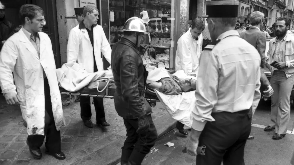 FILE - Rescuers carry an injured person on a stretcher from the scene of a terror attack at the Jo Goldenberg restaurant in Paris, France, Aug. 9, 1982. (AP Photo/Lionel Cironneau, File)
