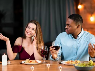 Annoyed African Man Looking At His Girlfriend Talking On Mobile Phone During Romantic Dinner In Restaurant, Complaining About Her Cellphone Addiction. Interracial Couple Having Communication Problems,Image: 1017031699, License: Royalty-free, Restrictions:, Model Release: no