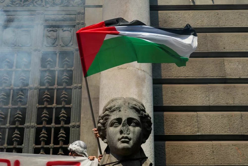 A demonstrator waves a Palestinian flag near a statue, during a nationwide strike called by the USB union, with the slogan "Let's Block Everything", in solidarity with Gaza and calling for a halt to arms shipments to Israel, in Naples, Italy, September 22, 2025. REUTERS/Matteo Ciambelli
