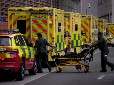 ﻿Paramedics push a trolley next to a line of ambulances outside the Royal London Hospital in the Whitechapel area of east London, Thursday, Jan. 6, 2022. Health authorities across the U.K. simplified COVID-19 testing requirements on Wednesday, a move designed to cut isolation times for many people and that may ease the staffing shortages that are hitting public services amid an omicron-fueled surge in coronavirus infections. A string of National Health Service local organizations have declared "critical incidents" in recent days amid staff shortages. (AP Photo/Matt Dunham)