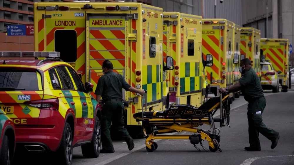 ﻿Paramedics push a trolley next to a line of ambulances outside the Royal London Hospital in the Whitechapel area of east London, Thursday, Jan. 6, 2022. Health authorities across the U.K. simplified COVID-19 testing requirements on Wednesday, a move designed to cut isolation times for many people and that may ease the staffing shortages that are hitting public services amid an omicron-fueled surge in coronavirus infections. A string of National Health Service local organizations have declared "critical incidents" in recent days amid staff shortages. (AP Photo/Matt Dunham)