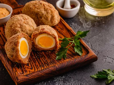 Traditional Scotch Eggs on a wooden board, on a dark background. / Foto: Tbralnina