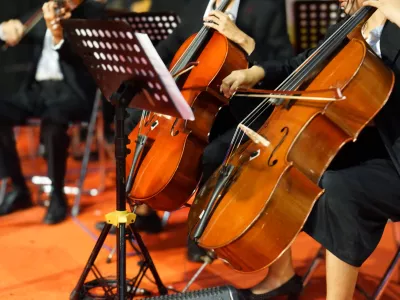 Hands playing cello orchestra with note sheet on stage. / Foto: Yori Meirizan