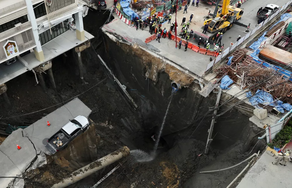A vehicle teeters on the edge of a massive sinkhole that opened on Samsen Road near Vajira Hospital, in Bangkok, Thailand, September 24, 2025. REUTERS/Chalinee Thirasupa