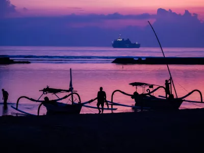 FILED - 14 November 2022, Indonesia, Nusa Dua: Men attach boats to the beach of Nusa Dua before sunrise on the day before the start of the G20 summit, with an Indonesian Navy ship visible in the background. Starting next year, tourists entering the Indonesian resort island of Bali will have to pay a fee of ten US dollars (nine euros) per person. Photo: Christoph Soeder/dpa