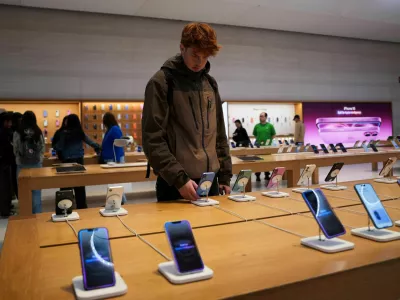 FILE PHOTO: A person looks at iPhones in the Apple Fifth Avenue store in New York City, U.S., May 23, 2025. REUTERS/Adam Gray/File Photo