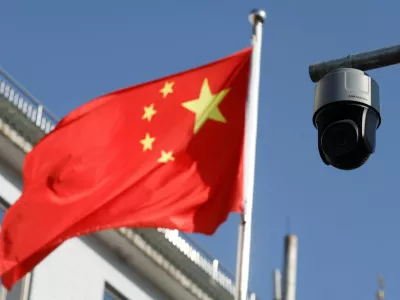 FILE PHOTO: A security surveillance camera overlooking a street is pictured next to a nearby fluttering flag of China in Beijing, China November 25, 2021. Picture taken November 25, 2021. REUTERS/Carlos Garcia Rawlins/File Photo