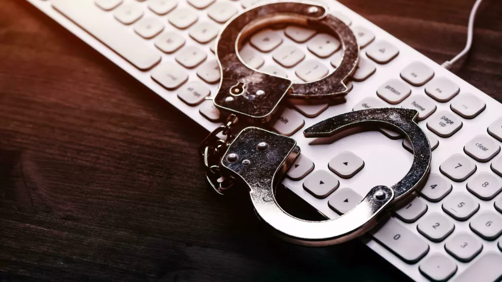 2TDENA2 High tech IT cyber crime arrest concept, image of police handcuffs over computer keyboard, selective focus