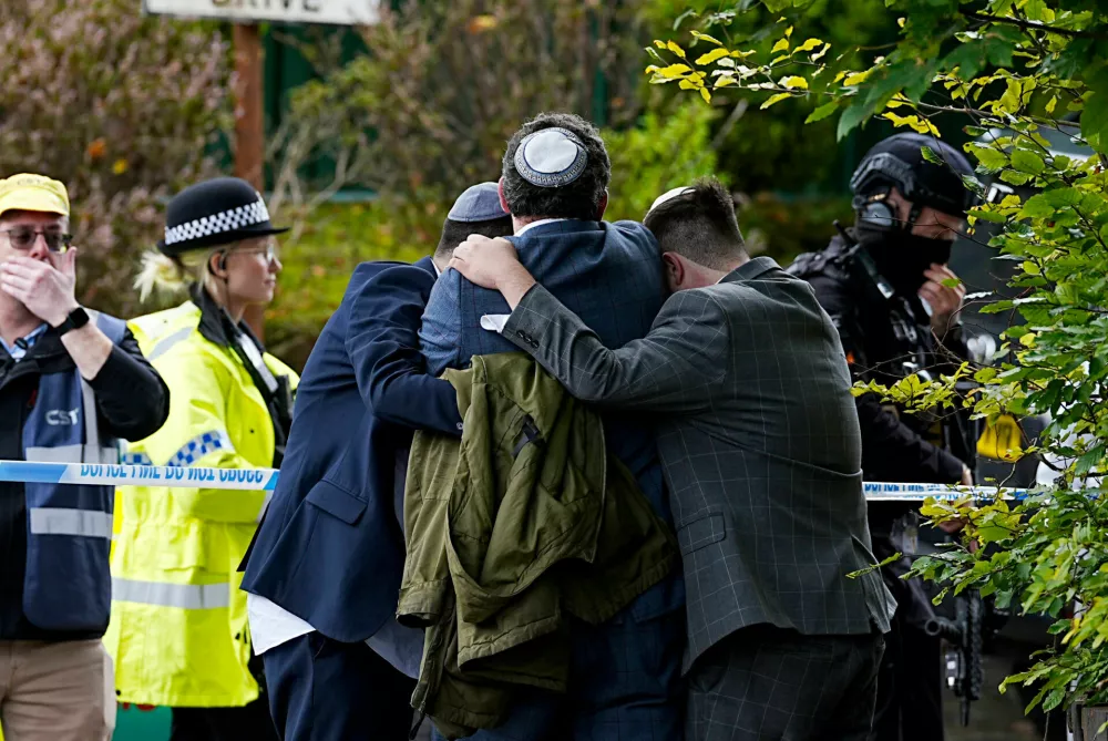 Members of the Jewish community comfort each other near to the Heaton Park Hebrew Congregation synagogue, in Crumpsall, Manchester, England, Thursday, Oct. 2, 2025 after Police reported that two people were killed and three others were seriously injured in a synagogue attack in northern England. (Peter Byrne/PA via AP)