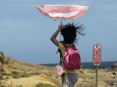 ﻿A girl struggles with winds from approaching Typhoon Matmo along the eastern coast of Keelung, northeastern Taiwan, Tuesday, July 22, 2014. The eye of Typhoon Matmo is expected to make landfall in eastern Taiwan early Wednesday bringing heavy rain and winds with gusts over 130 kilometers (85 miles) per hour. (AP Photo/Wally Santana)