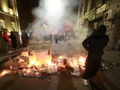 A demonstrator stands behind a burning barricade not far from a police line during an opposition rally in the city center of Tbilisi, Georgia, on Sunday, Oct. 5, 2025, boycotting the municipal elections and calling for the release of political opponents. (AP Photo/Zurab Tsertsvadze)