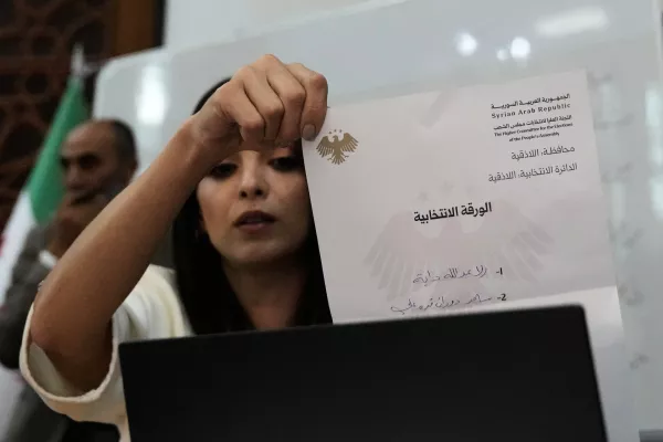 A Syrian election official shows a ballot paper during the counting of ballots, shortly after polling stations closed at Latakia's Governor building, in the coastal city of Latakia, Syria, Sunday, Oct. 5, 2025. (AP Photo/Hussein Malla)