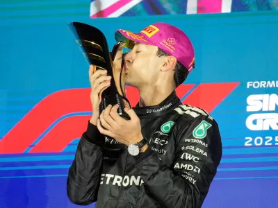 Mercedes driver George Russell of Britain kisses his trophy as he celebrates after winning the Singapore Formula One Grand Prix at the Marina Bay Street Circuit in Singapore, Sunday, Oct. 5, 2025. (AP Photo/Vincent Thian)