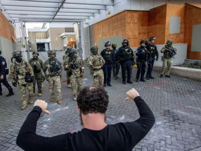 A protester stands off against police and federal officers at a U.S. Immigration and Customs Enforcement facility in Portland, Ore. on Sunday, Oct. 5, 2025. (AP Photo/Ethan Swope)