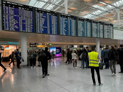 People walk past the departure board at the airport in Munich, after it was gradually resuming flights with delays expected through the day, hours after both runways were closed for the second time in less than 24 hours due to a drone sighting, in Munich, Germany, October 4, 2025. REUTERS/Ayhan Uyanik