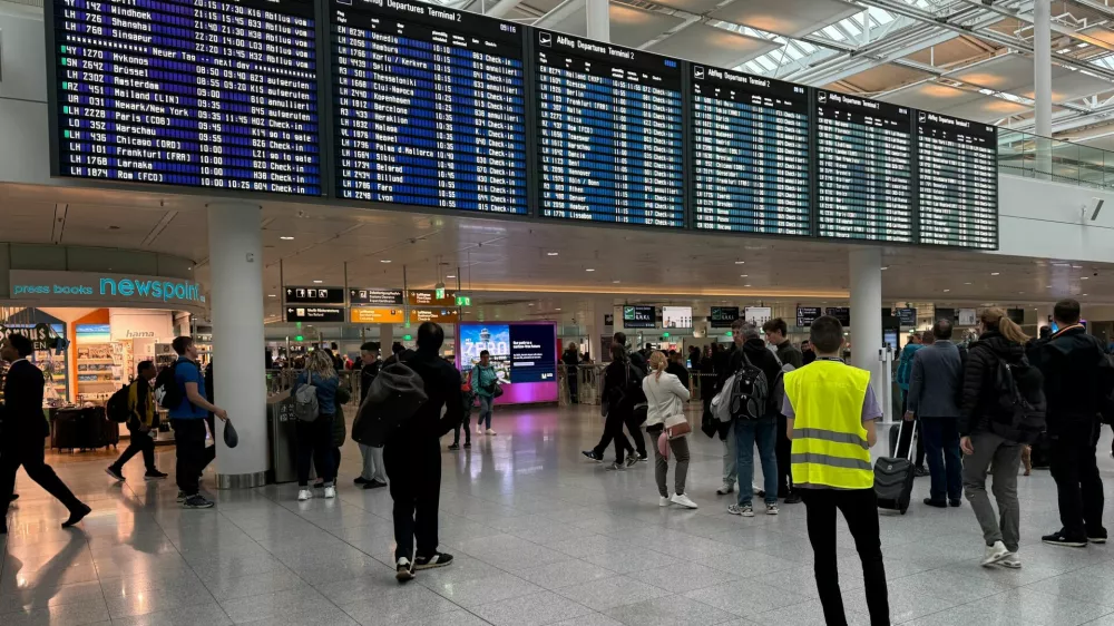 People walk past the departure board at the airport in Munich, after it was gradually resuming flights with delays expected through the day, hours after both runways were closed for the second time in less than 24 hours due to a drone sighting, in Munich, Germany, October 4, 2025. REUTERS/Ayhan Uyanik