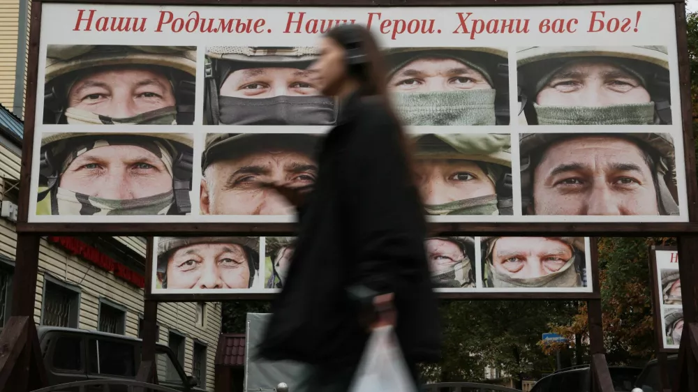 A woman walks past a gallery of portraits of Russian service members involved in the country's military campaign in Ukraine, that is placed in a street near the office of a charity fund collecting donations on vehicles for the use of Russia's army during a conflict against Ukraine, in Saint Petersburg, Russia, October 6, 2025. A slogan on the board reads: "Our dear ones. Our heroes. God bless you!" REUTERS/Anton Vaganov