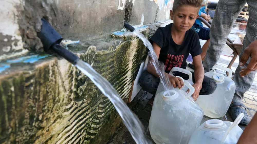 A displaced Palestinian boy fills a container with water, in Deir Al-Balah, central Gaza Strip, October 8, 2025. REUTERS/Dawoud Abu Alkas