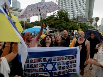 Einav Zangauker, the mother of hostage Matan Zangauker, reacts holding an Israeli flag with photos of hostages, after U.S. President Donald Trump announced that Israel and Hamas agreed on the first phase of a Gaza ceasefire, at the "Hostages square", in Tel Aviv, Israel, October 9, 2025. REUTERS/Ronen Zvulun