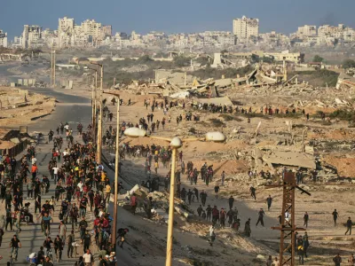 Israeli tanks are positioned on the coastal road leading to Gaza City as displaced Palestinians gather near Wadi Gaza in the central Gaza Strip, Thursday, Oct. 9, 2025. (AP Photo/Abdel Kareem Hana)
