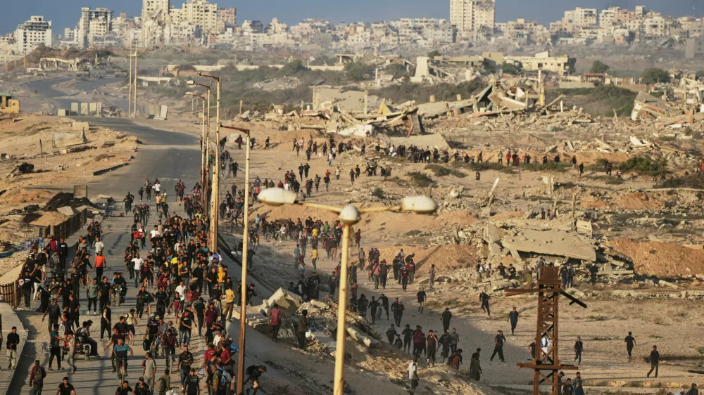 Israeli tanks are positioned on the coastal road leading to Gaza City as displaced Palestinians gather near Wadi Gaza in the central Gaza Strip, Thursday, Oct. 9, 2025. (AP Photo/Abdel Kareem Hana)