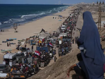 Displaced Palestinians ride on trucks loaded with belongings and wave Egyptian and Palestinian flags as they travel along the coastal road near Wadi Gaza in the central Gaza Strip, moving toward Gaza city, Saturday, Oct. 11, 2025, after Israel and Hamas agreed to a pause in their war and the release of the remaining hostages. (AP Photo/Jehad Alshrafi)