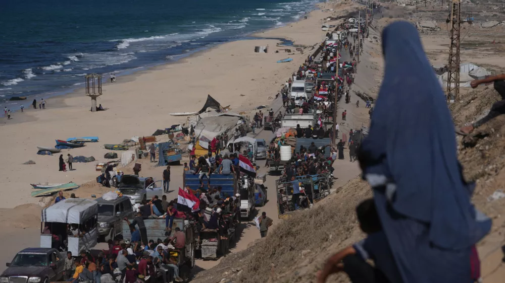 Displaced Palestinians ride on trucks loaded with belongings and wave Egyptian and Palestinian flags as they travel along the coastal road near Wadi Gaza in the central Gaza Strip, moving toward Gaza city, Saturday, Oct. 11, 2025, after Israel and Hamas agreed to a pause in their war and the release of the remaining hostages. (AP Photo/Jehad Alshrafi)