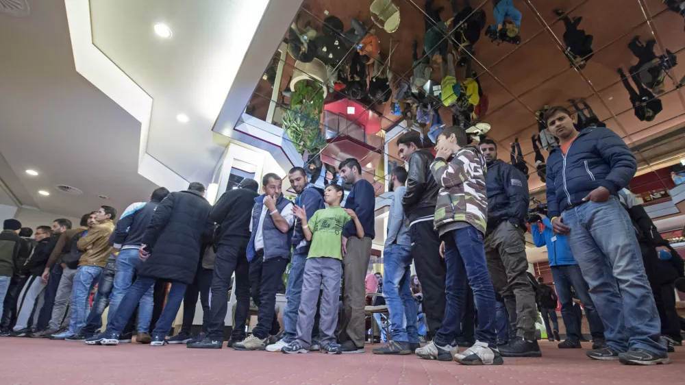 ﻿People line up for their meal in the initial reception center for asylum seekers in Halle/Saale, Germany, Friday, Oct. 16, 2015. The center in a former hotel has capacity for around 700 refugees. (AP Photo/Jens Meyer)