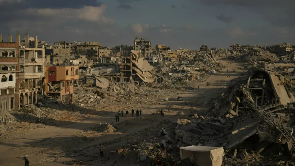 Palestinians walk among destroyed buildings in Gaza City, Sunday, Oct. 12, 2025, after Israel and Hamas agreed to a pause in their war and the release of the remaining hostages. (AP Photo/Jehad Alshrafi)