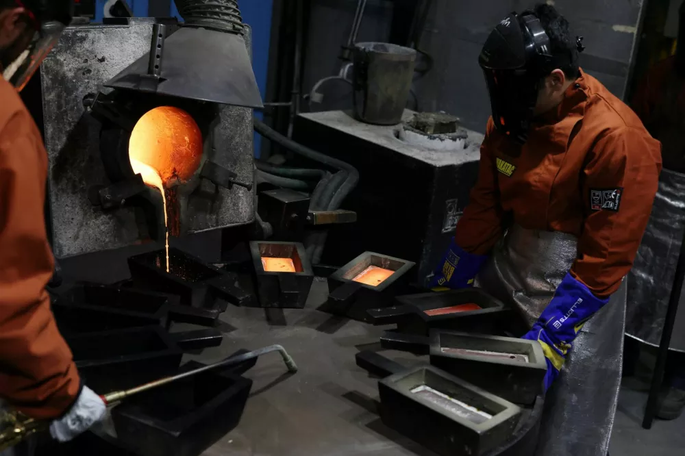 Production workers watch as molten gold dore falls into moulds at ABC Refinery in Sydney, Australia, October 13, 2025. REUTERS/Hollie Adams