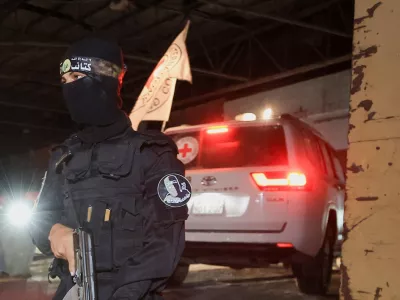 An armed Hamas militant stands guard as a Red Cross vehicle arrives to receive from Hamas militants the bodies of deceased hostages who had been held in Gaza since the deadly October 7, 2023 attack, as part of a ceasefire and a hostages-prisoners swap deal between Hamas and Israel, in Gaza City, October 14, 2025. REUTERS/Dawoud Abu Alkas
