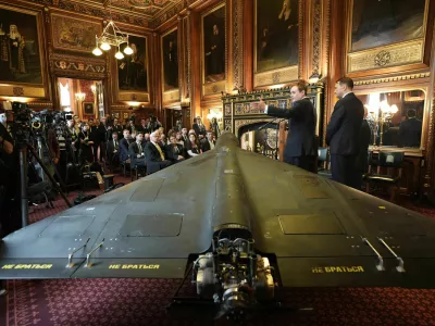Britain's former security minister Tom Tugendhat, second right, and Polish foreign minister Radek Sikorski speak in front of a downed Russian's army Shahed-136 attack drone, during a press conference organised by United Against Nuclear Iran (UANI), in Speaker's Court at the House of Commons, Westminster, London, Tuesday, Oct. 14, 2025. (Stefan Rousseau/PA via AP)