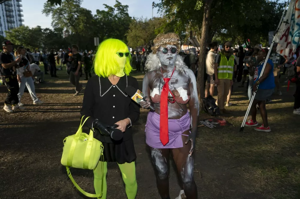 August 22, 2024, Chicago, Illinois, USA: The performer CRACKHEAD BARNEY speaks to a woman wearing a bright green wig, mask, and leggings in a reference to 'brat' at the March on the DNC 2024 Protest at Union Park in downtown Chicago.,Image: 900875822, License: Rights-managed, Restrictions:, Model Release: no