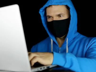 Moški za računalnikom z masko na obrazu