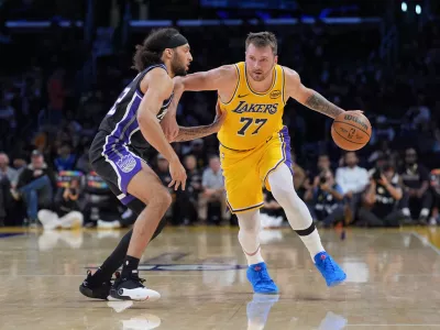 Los Angeles Lakers guard Luka Doncic (77) works around Sacramento Kings guard Devin Carter (22) during the first half of a preseason NBA basketball game Friday, Oct. 17, 2025, in Los Angeles. (AP Photo/Jae C. Hong)