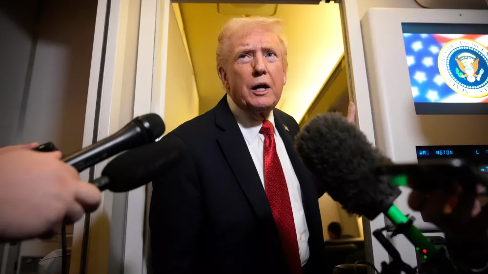 President Donald Trump speaks to reporters aboard Air Force One, Sunday, Oct. 19, 2025, en route to Joint Base Andrews, Md., as he returns from a trip to Florida. (AP Photo/Mark Schiefelbein)