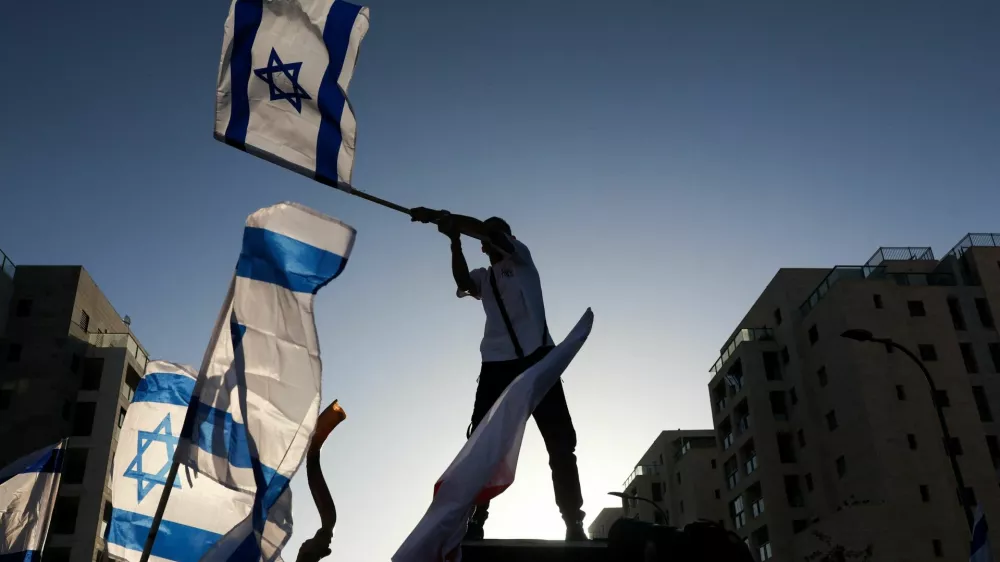 A man waves an Israeli flag as family and supporters gather on the day former Israeli hostage Elkana Bohbot returns home after leaving the hospital, following his release from captivity in Gaza, in Mevaseret Zion, Israel, October 19, 2025. REUTERS/Ronen Zvulun
