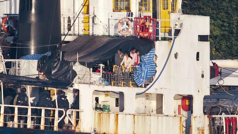 Some the estimated 490 people thought to be Tamil migrants aboard the ship MV Sun Sea peer out from underneath a tarp after Canadian Border officials and police brought the ship into Canadian Forces Base Esquimalt in Colwood, British Columbia on Vancouver Island August 13, 2010. Authorities intercepted and boarded the ship after it entered Canadian waters.     REUTERS/Andy Clark   (CANADA - Tags: CIVIL UNREST SOCIETY POLITICS IMAGES OF THE DAY)