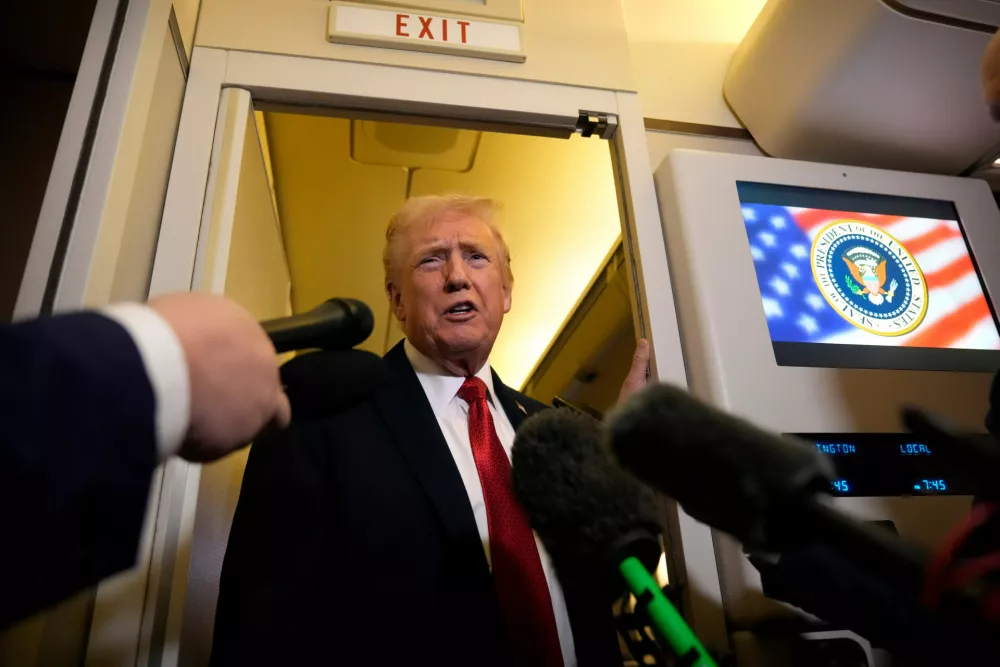 President Donald Trump speaks to reporters aboard Air Force One, Sunday, Oct. 19, 2025, en route to Joint Base Andrews, Md., as he returns from a trip to Florida. (AP Photo/Mark Schiefelbein)