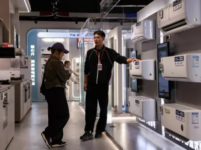 A staff member attends to a customer at an air conditioner booth at a home appliance mall in Beijing, China October 19, 2025. REUTERS/Tingshu Wang