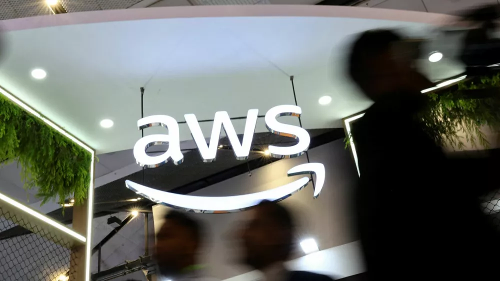 FILE PHOTO: People walk past the logo of Amazon Web Services (AWS) at its exhibitor stall at the India Mobile Congress 2025 at Yashobhoomi, a convention and expo center in New Delhi, India, October 8, 2025. REUTERS/Anushree Fadnavis/File Photo