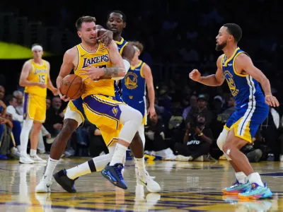 Los Angeles Lakers' Luka Dončić, left, is defended by Golden State Warriors guard Jonathan Kuminga during the first half of an NBA basketball game Tuesday, Oct. 21, 2025, in Los Angeles. (AP Photo/Ethan Swope)